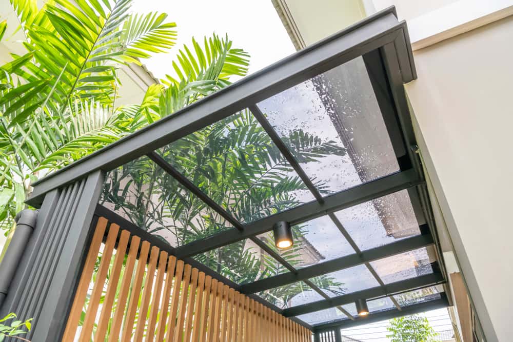 Contemporary polycarbonate roof design with sleek black framing and greenery