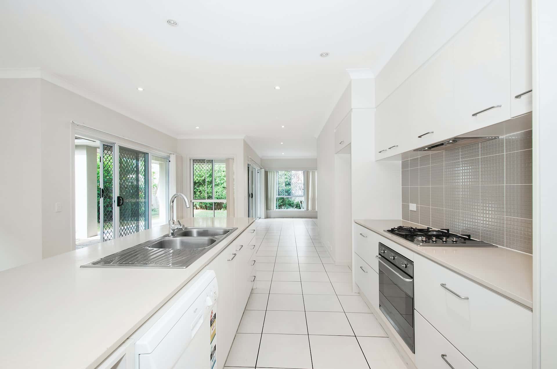 Minimal kitchen with sleek wall moulding designs, white cabinetry, and tiled backsplash