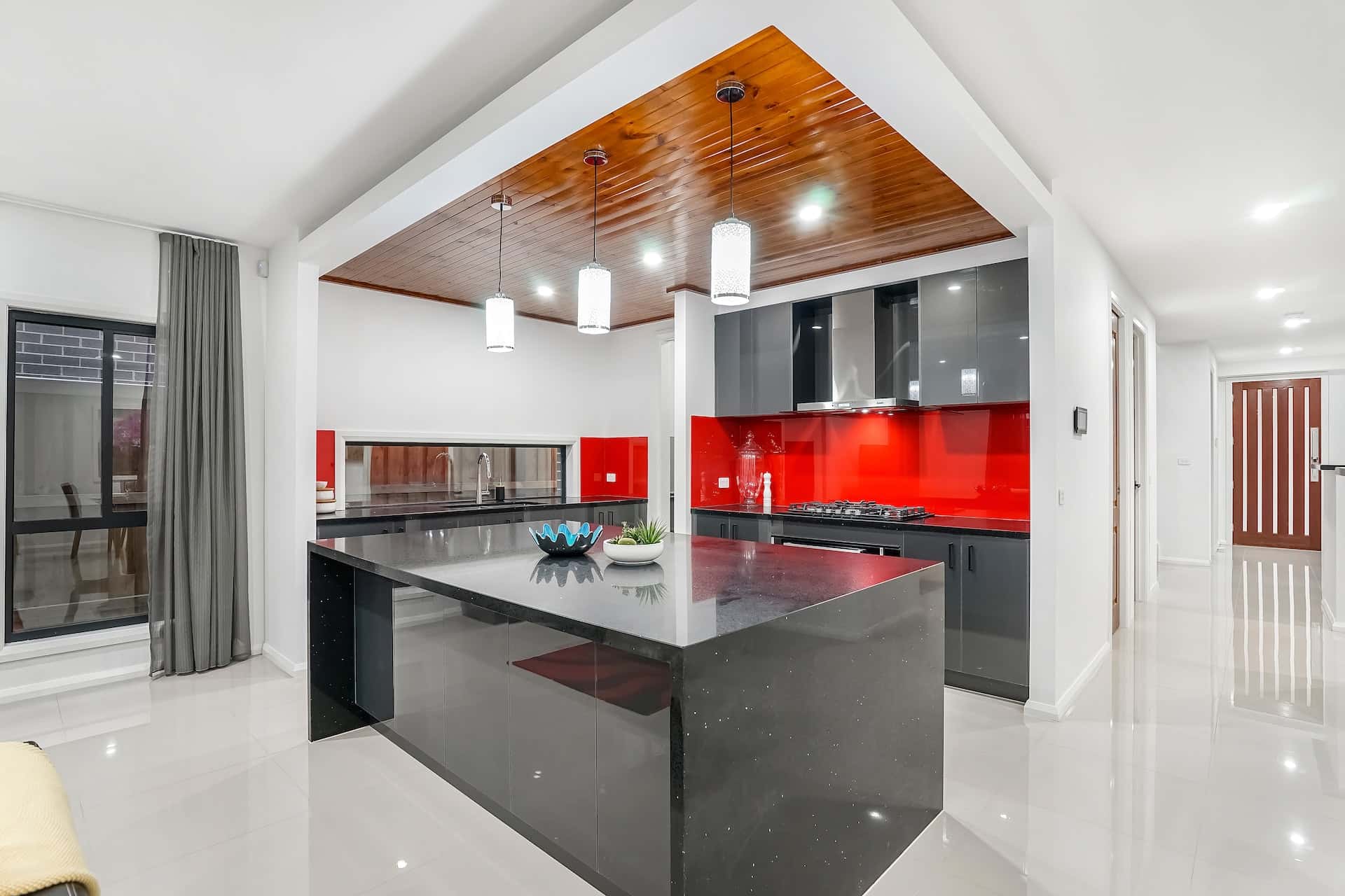 Bold sleek kitchen modular designs featuring glossy black cabinets and red glass backsplash
