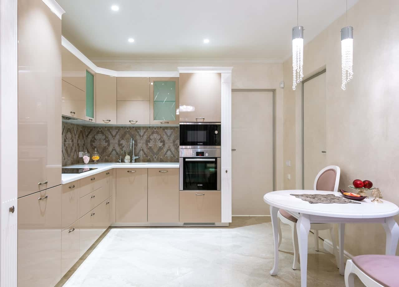 Elegant modern glass modular kitchen with glossy cabinets and cozy dining setup