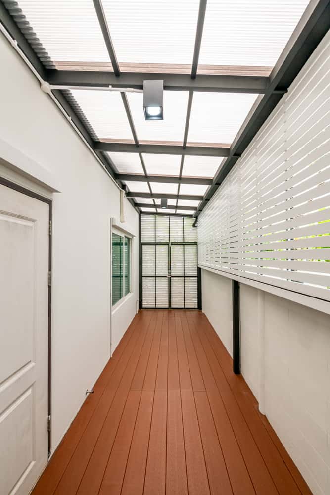 Minimal hallway polycarbonate roof design with white panels and wood flooring