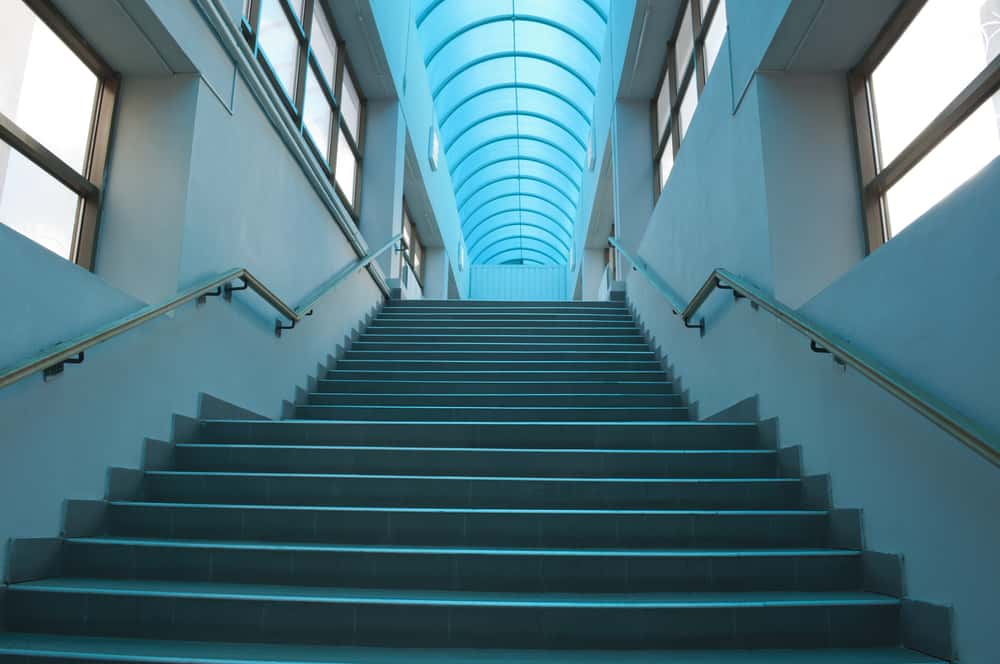 Modern staircase with blue polycarbonate roofing in a sunlit corridor