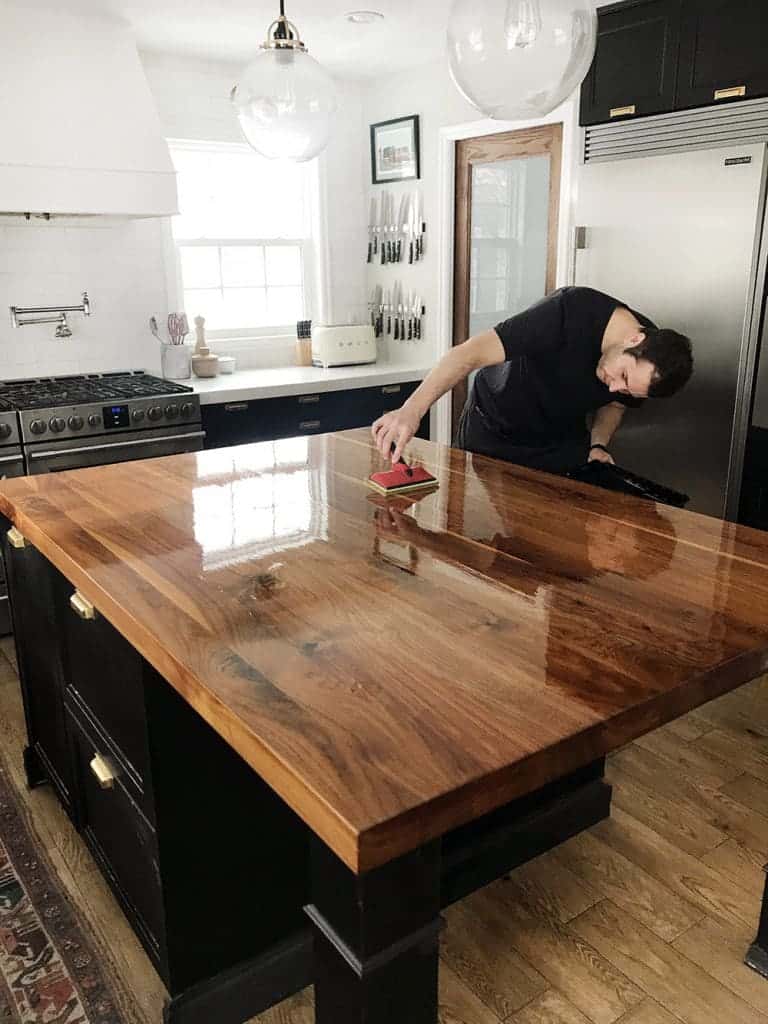 Simple Kitchen Platform Designs man polishing a large wooden kitchen island.