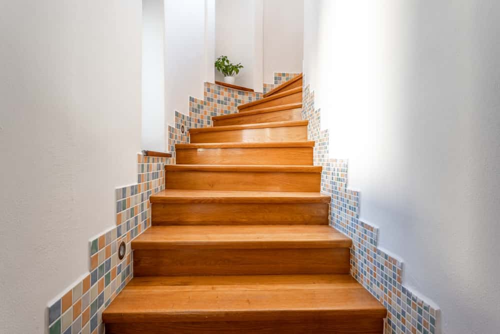 Curved wooden staircase tile designs paired with soft pastel mosaic wall accents