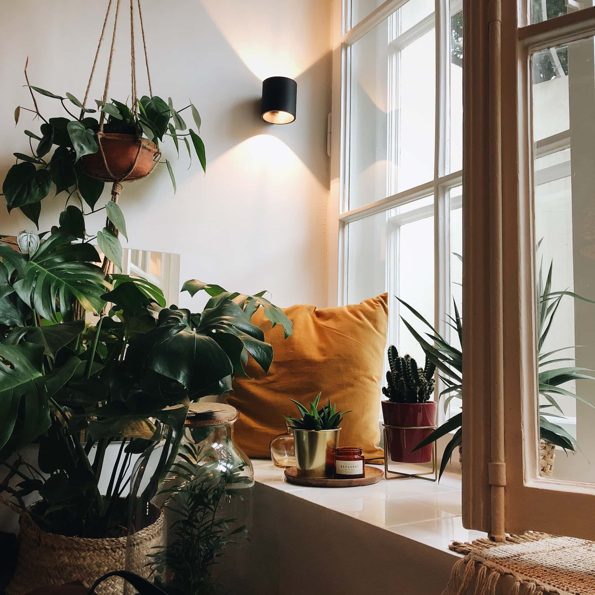 Peaceful closed balcony ideas with green plants and a cosy window seating nook