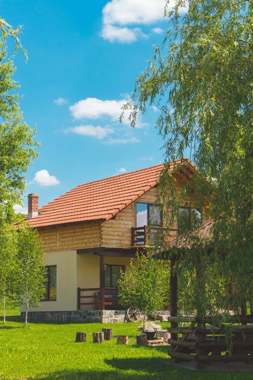 Rustic mangalore tile roof cabin with wooden balcony set in lush green countryside