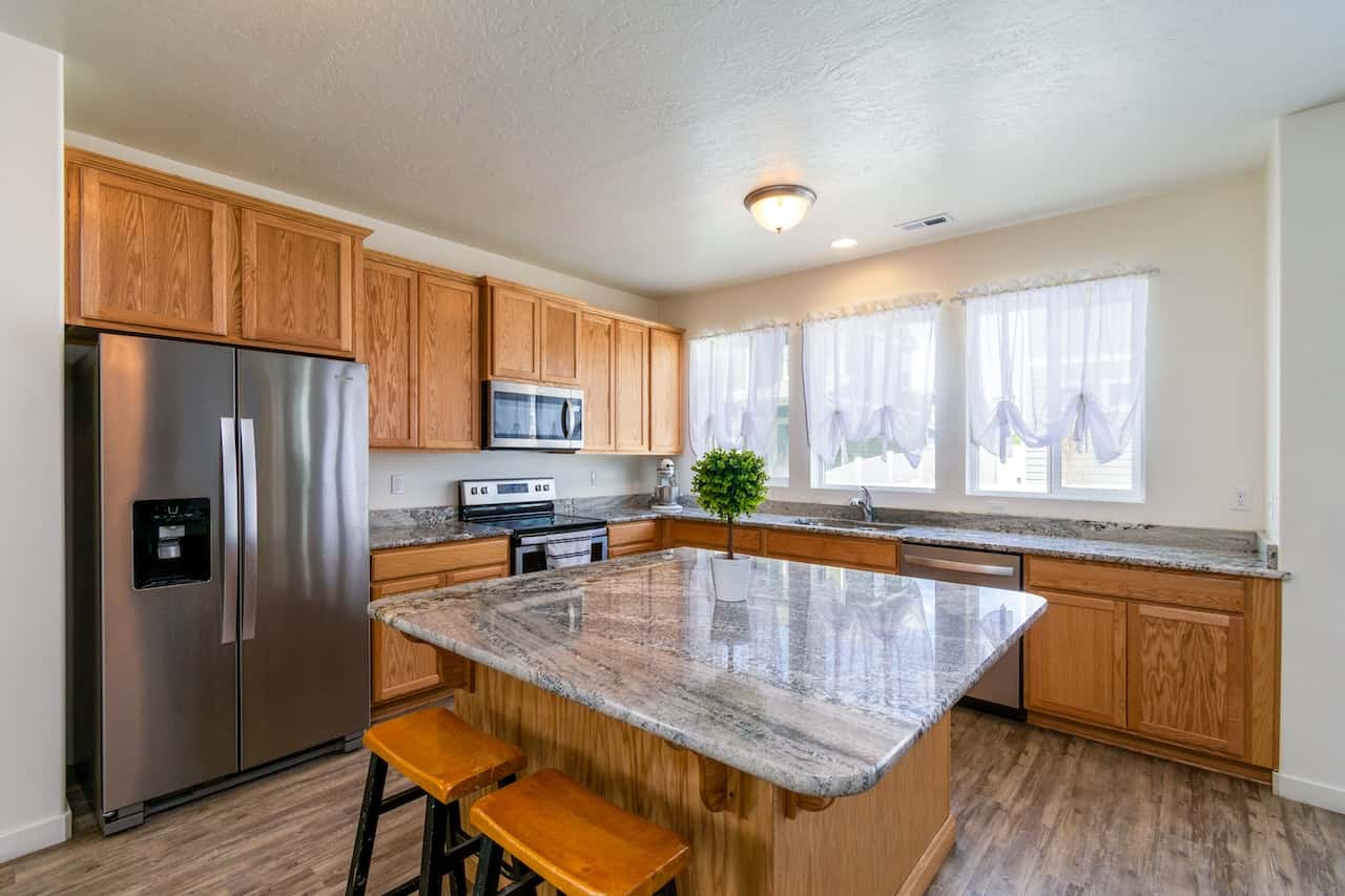 Wooden cabinets with granite kitchen platform and central island in natural light