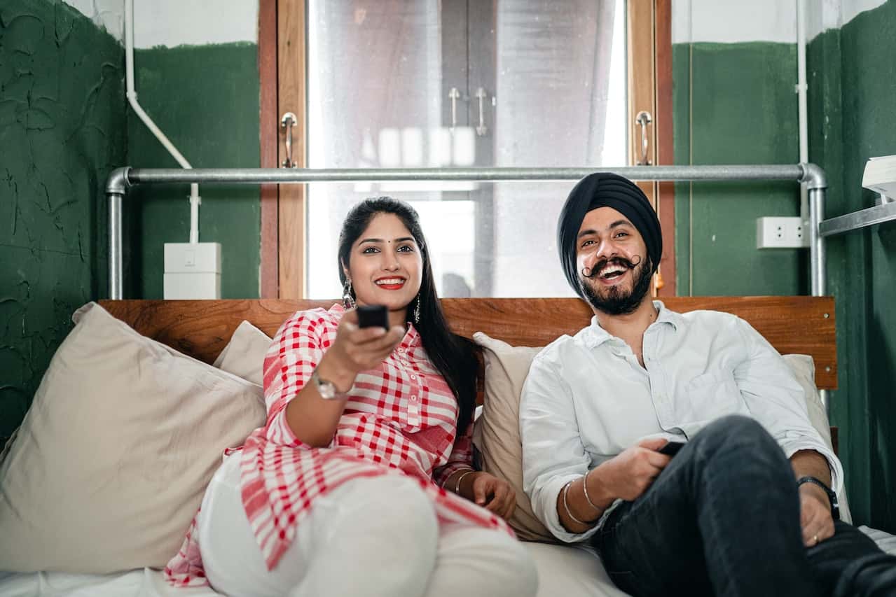 Couple relaxing with smart gadgets and electrical points in bedroom placed smartly