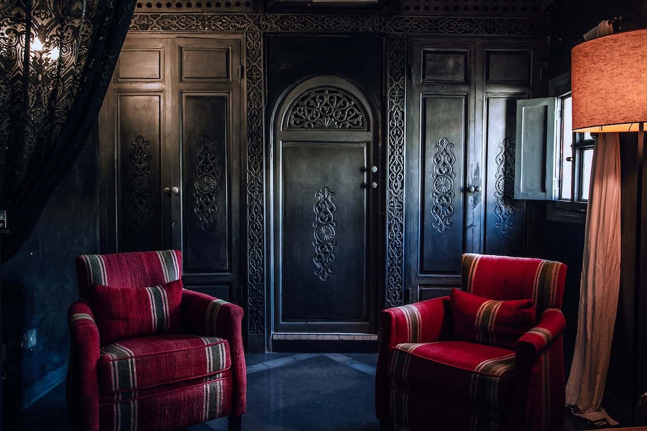 Dramatic haveli designs with carved wooden walls and bold red seating