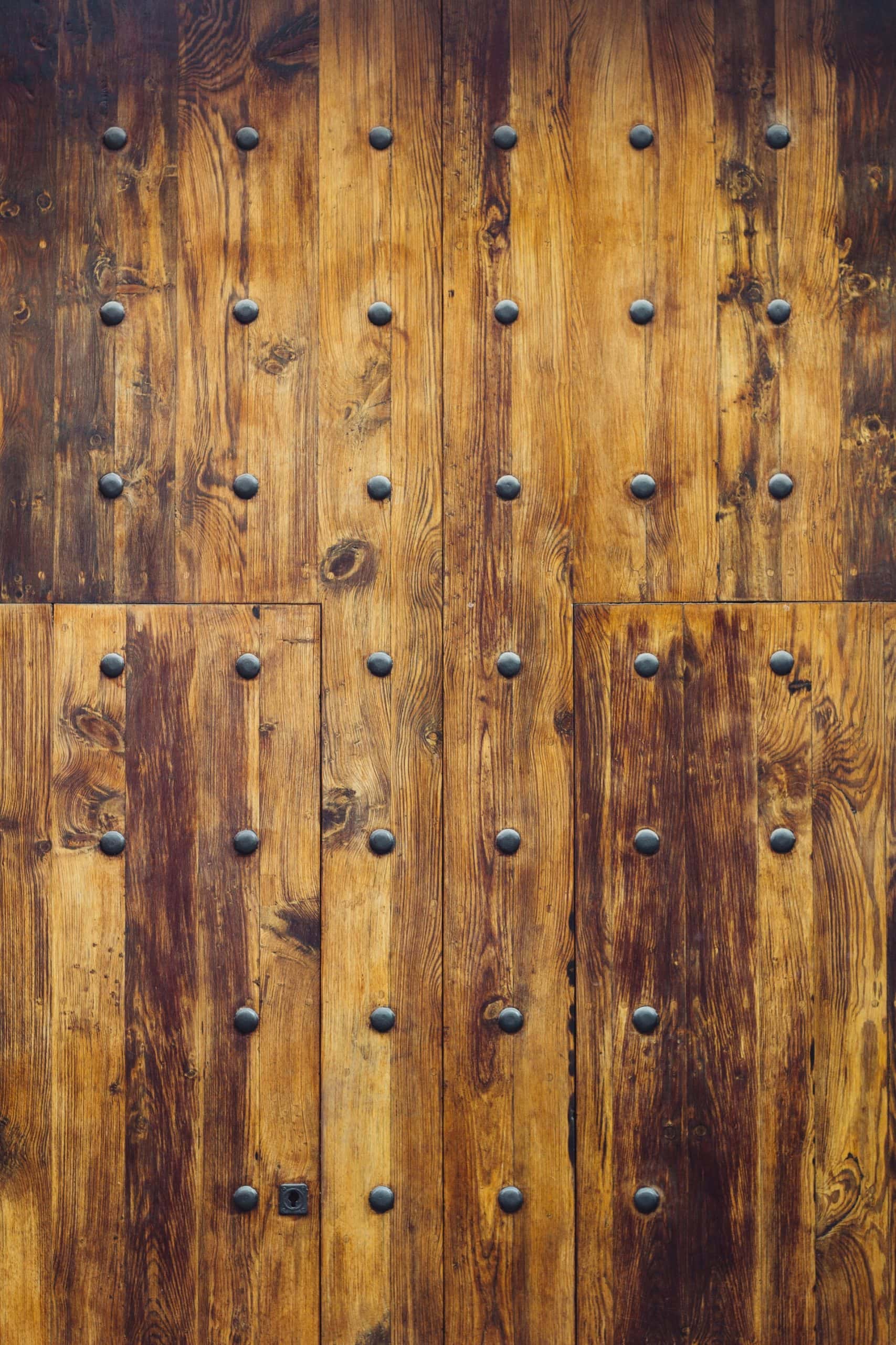 Vintage mandir door designs featuring polished wood and metallic rivets