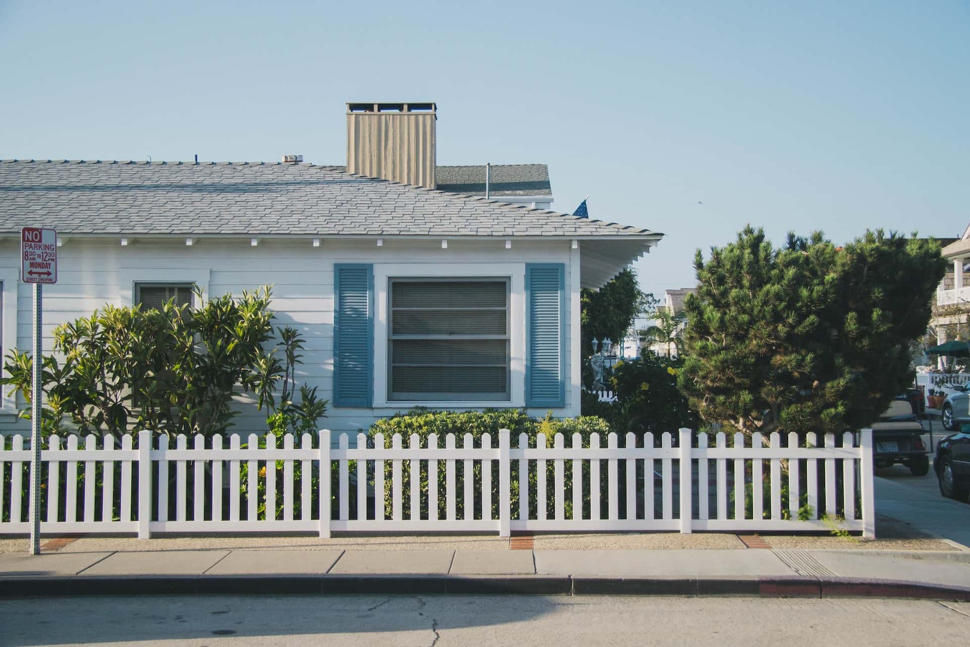 Compact l-shaped house design with picket fence and greenery