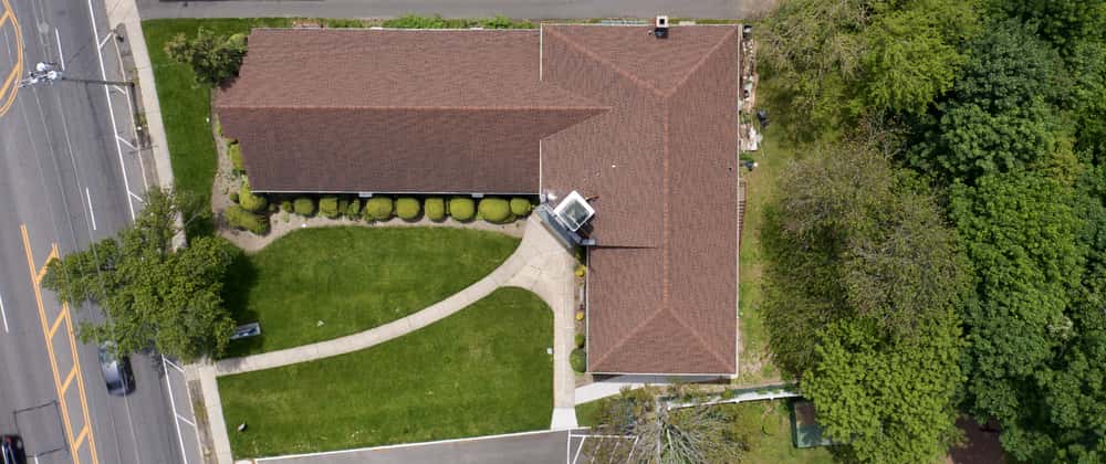 Aerial l-shaped house design with lush green landscape layout