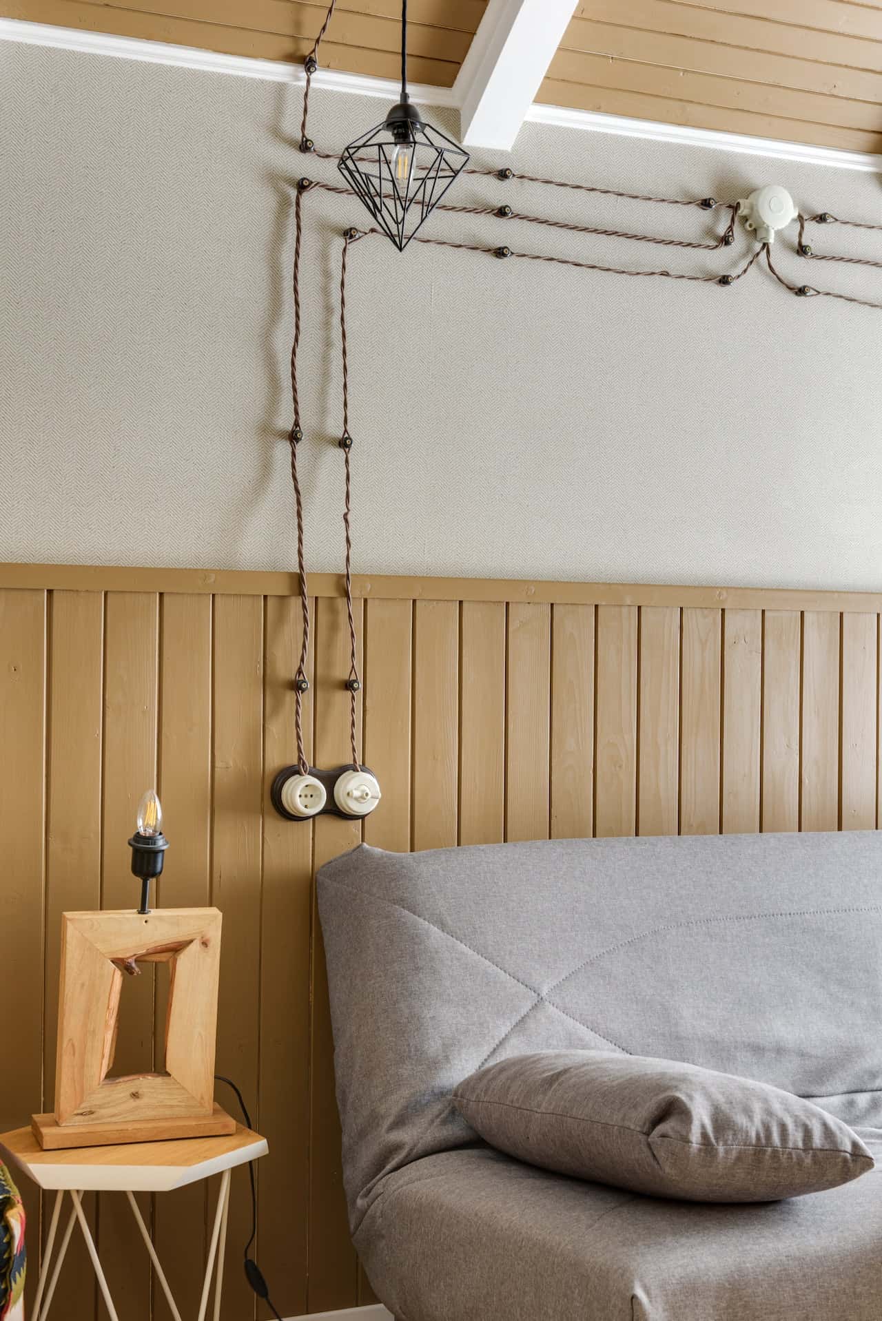 Vintage-style electrical points in bedroom with exposed twisted wiring and wooden walls
