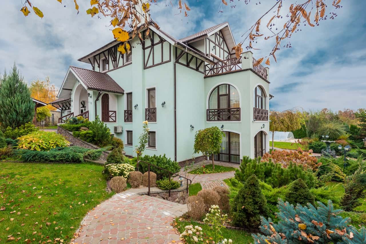 Grand assam type house design with arches, balcony, and landscaped garden