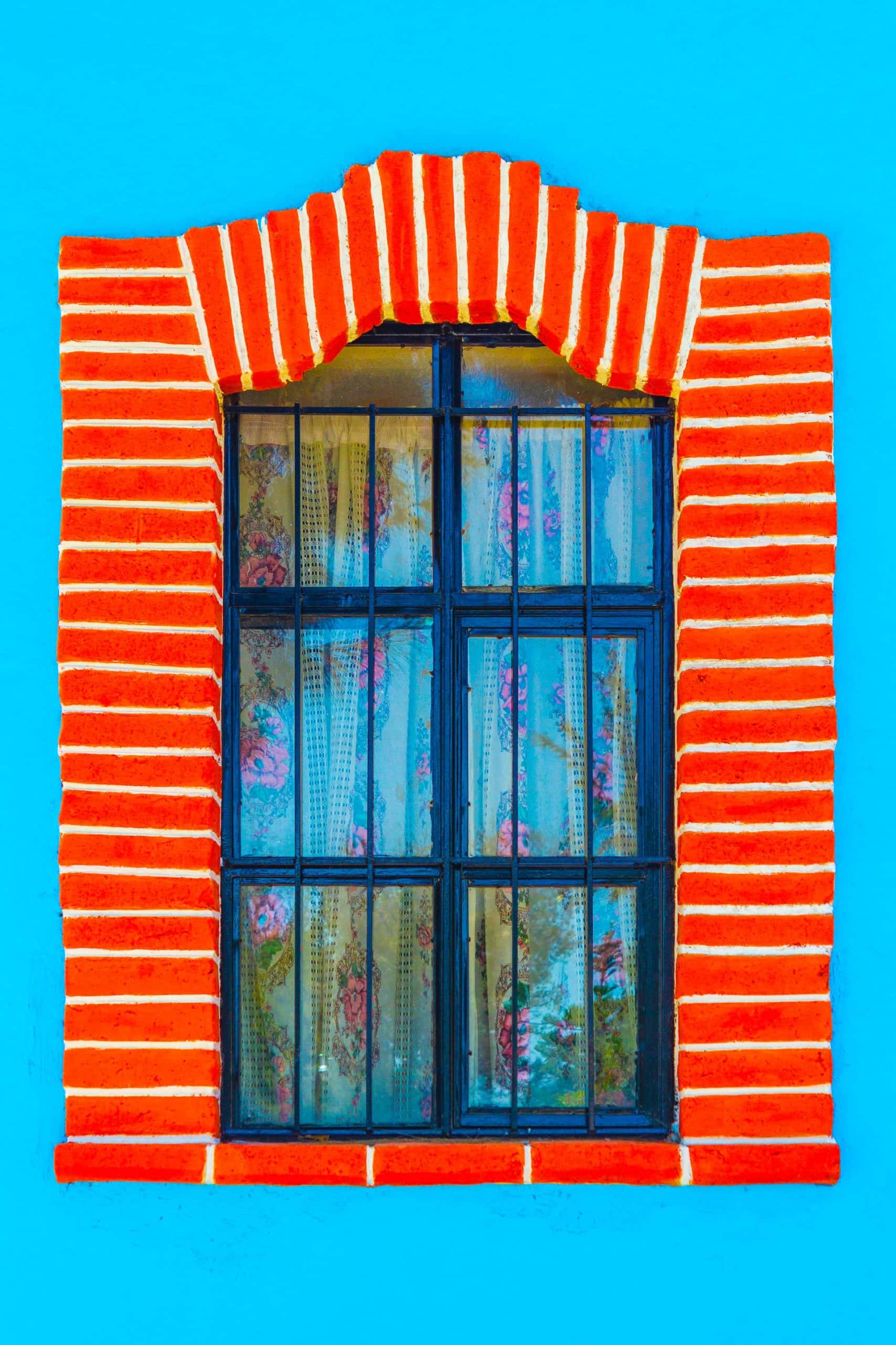 Vibrant sliding window grill design with red brick arch frame