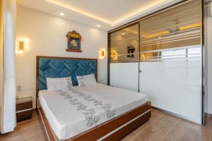 HomeLane serene master bedroom with blue quilted headboard and modern metallic wardrobe