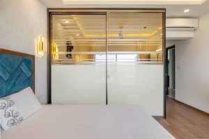 HomeLane master bedroom with modern sliding wardrobe doors and blue quilted headboard