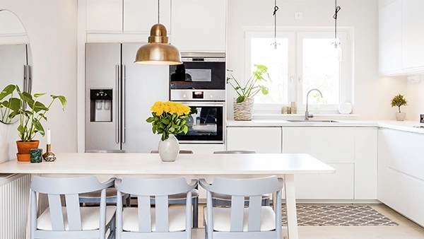 Bright kitchen triangle layout with dining table sink fridge and built-in oven in view