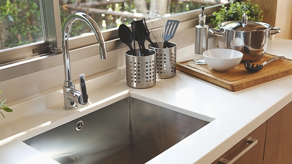 Modern sink zone in a kitchen triangle setup with utensils and cooking tools nearby