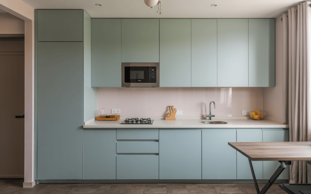 Clean simple small modular kitchen design with mint green cabinets and built-in microwave