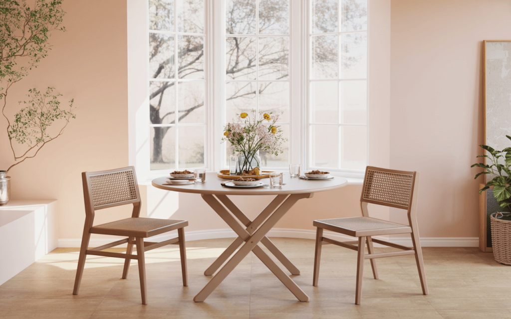 Chic round folding dining table set by the window in a bright, airy dining room