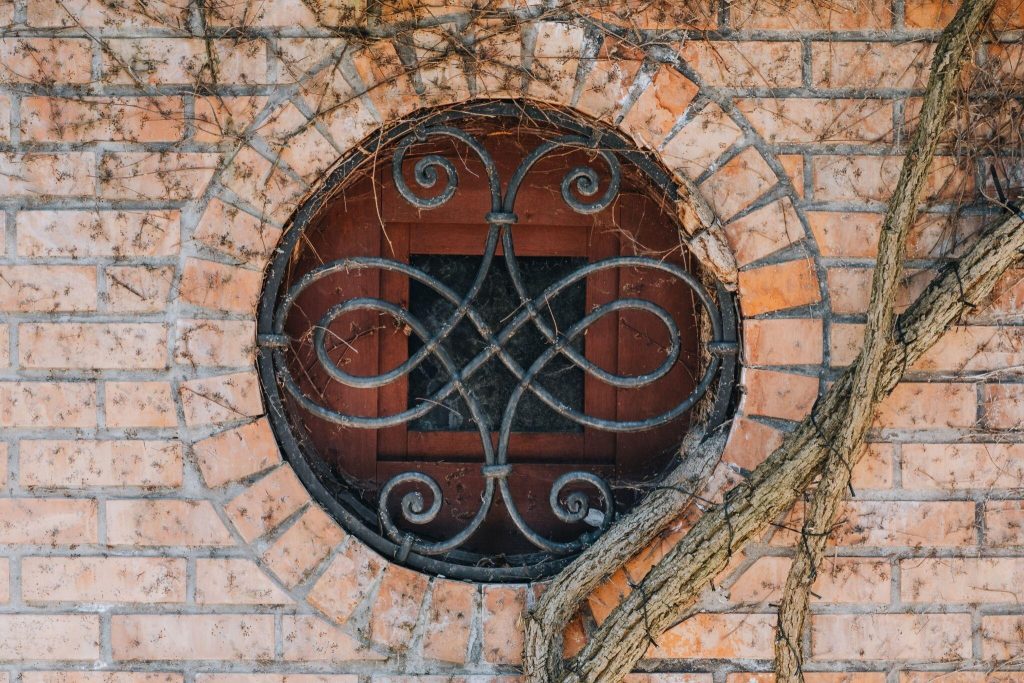 Vintage simple window grill design on round brick wall with rustic charm