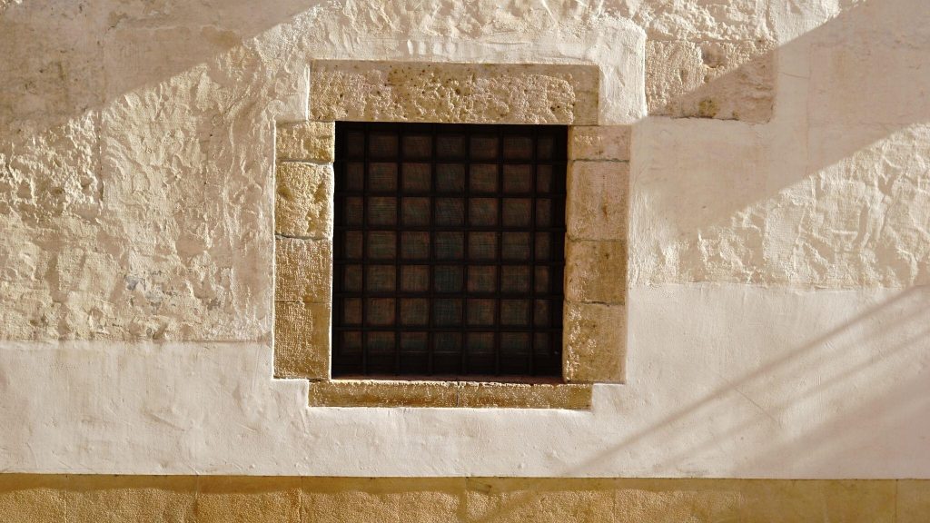 Classic simple modern window grill design blending with rustic stone wall and sunlight