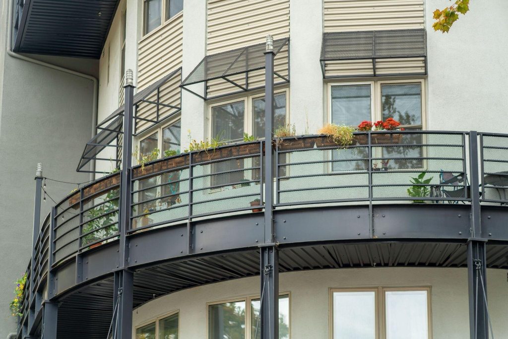 Curved simple front balcony design with black railing and potted green plants