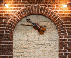 Modern Tamil Nadu house designs featuring artistic brick wall decor with a violin accent for rustic elegance