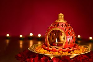 Festive party ideas for holi decor with diya lamp, flowers, and traditional red background