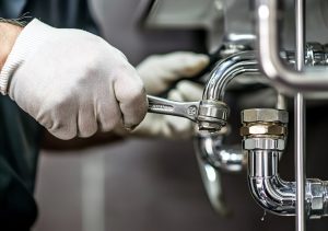 Plumbing kitchen renovation work showing pipe fittings and wrench adjustment