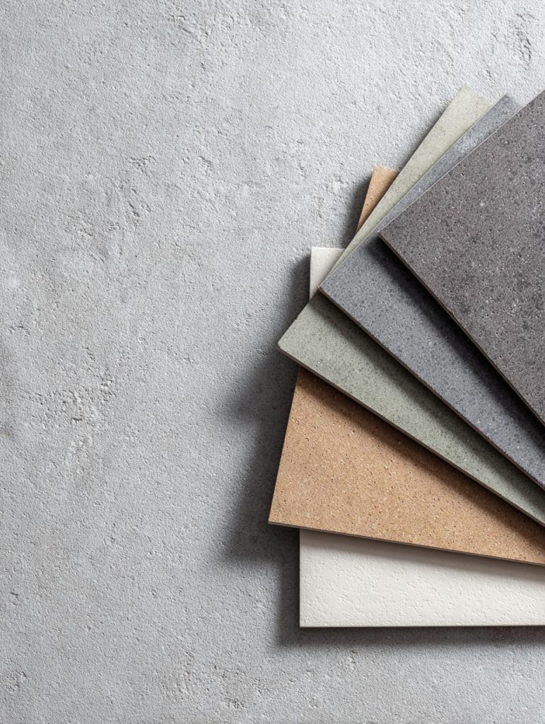 A collection of various vitrified tiles texture samples in earthy tones on a grey stone