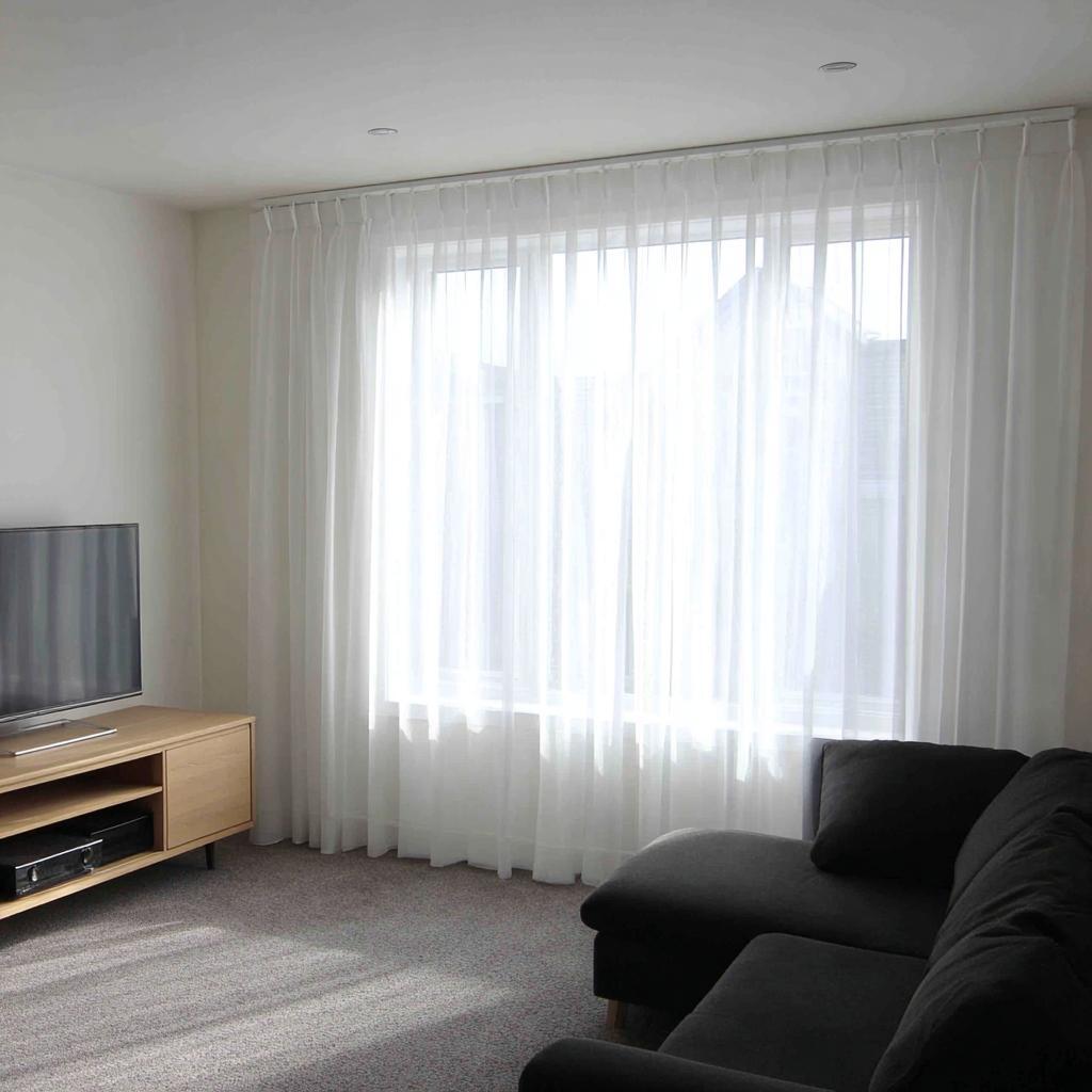 Cheap living room decor ideas with floor-to-ceiling sheer white curtains.