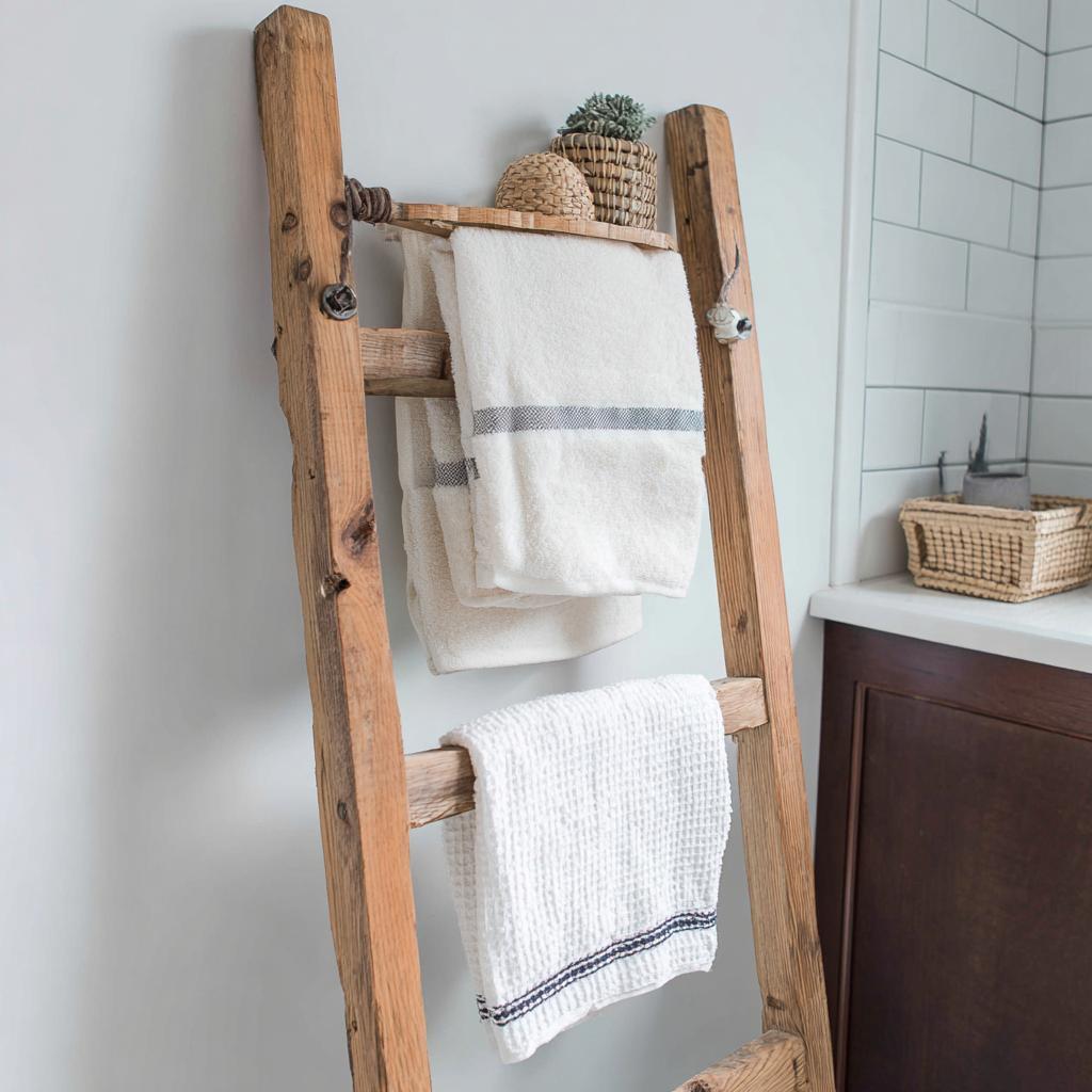 Cheap room decor items featuring a rustic wooden ladder for towel storage