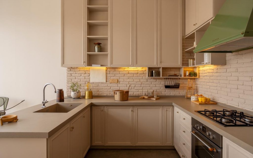Simple non modular kitchen design with beige cabinets and warm lighting on brick backsplash