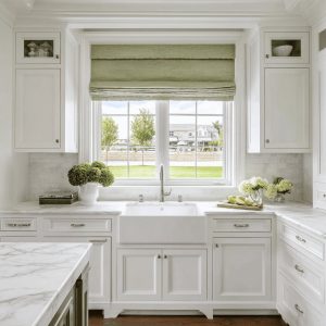 Elegant kitchen curtain design with soft green Roman shade enhancing bright classic white kitchen window