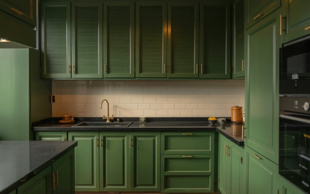 An elegant simple kitchen design low cost with olive green shutters and a black countertop.