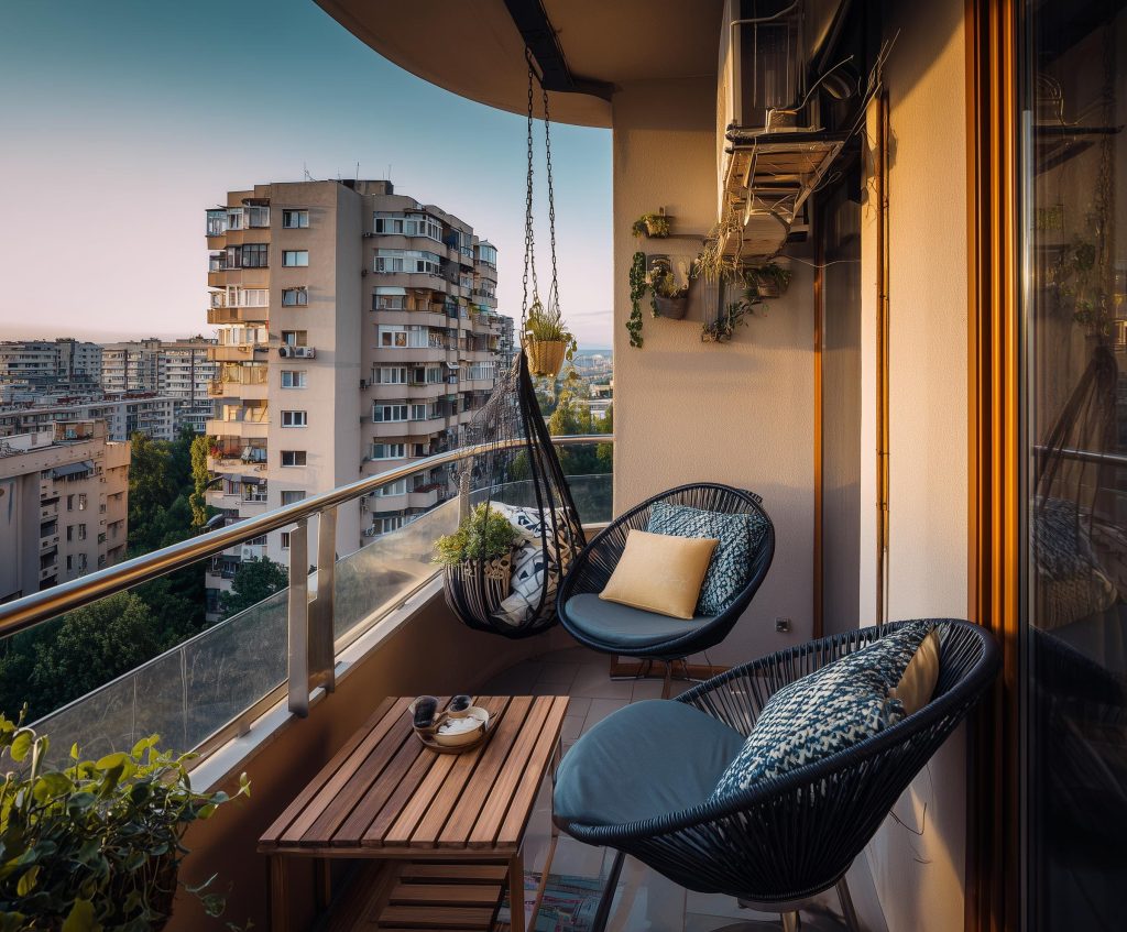 A modern metal hanging swing chair for balcony seating overlooking a scenic city skyline.