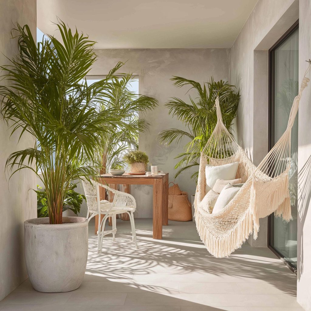  A white fringed hammock style swing for small balcony spaces paired with tropical palms.