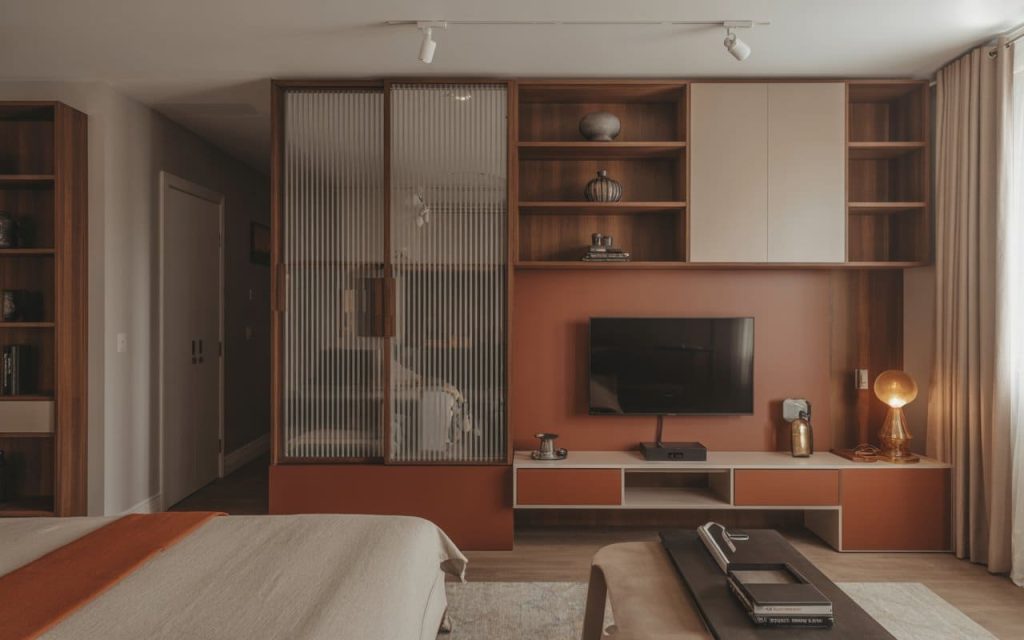 A modern bedroom interior design featuring a wooden TV unit and fluted glass partitions.