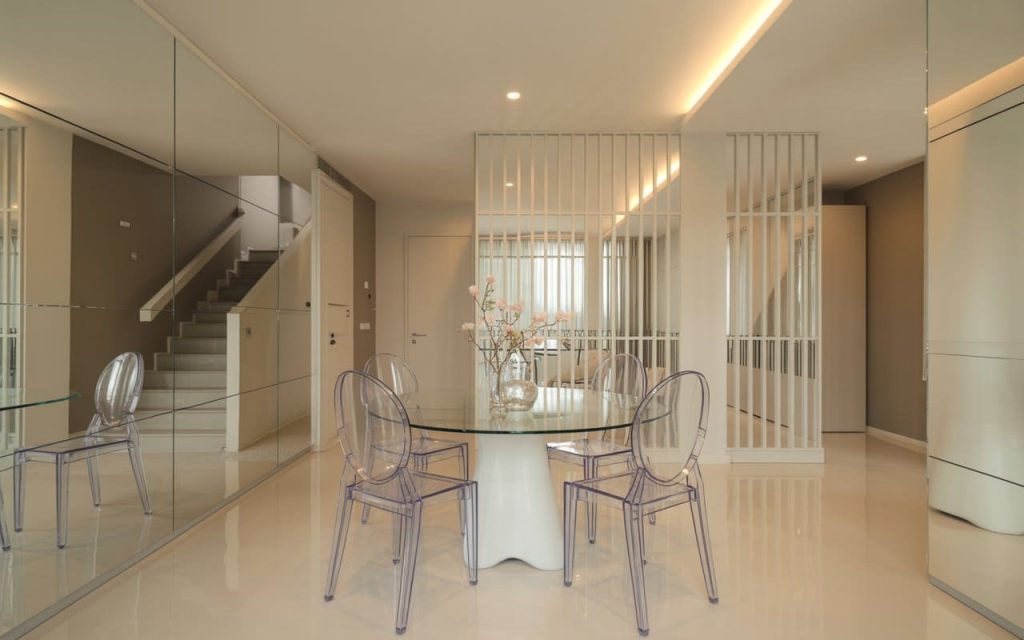 A hall interior design featuring mirrored walls and transparent acrylic dining chairs.