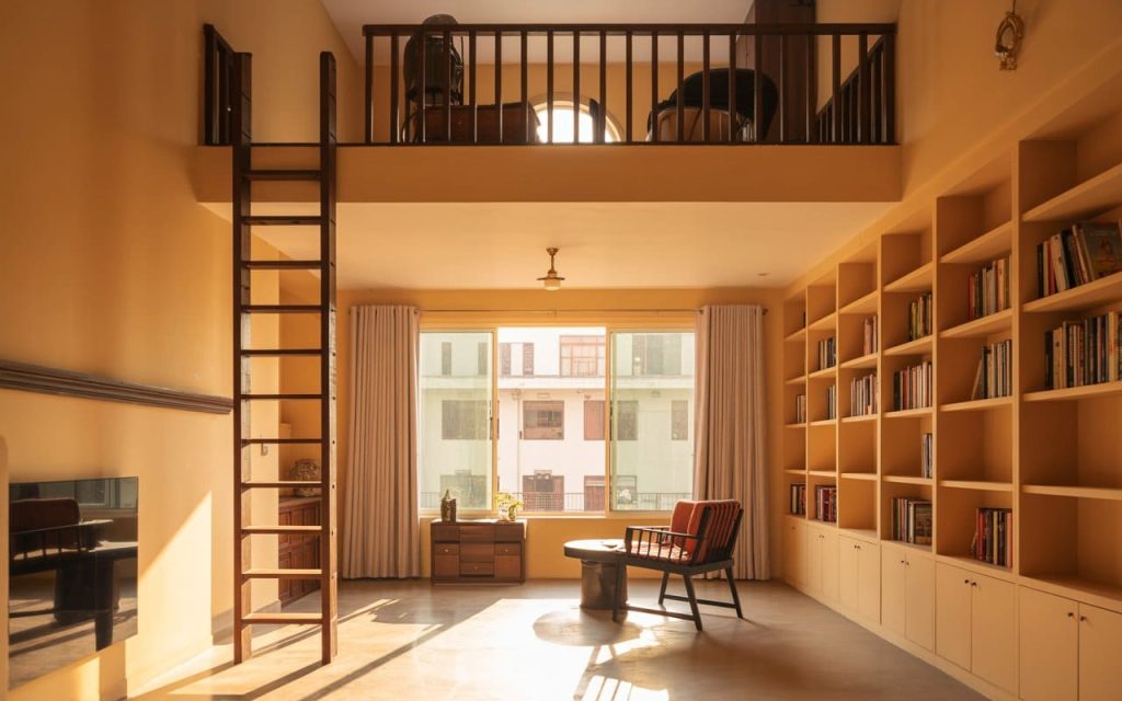 A spacious room interior design featuring a tall bookshelf and a lofted mezzanine level.