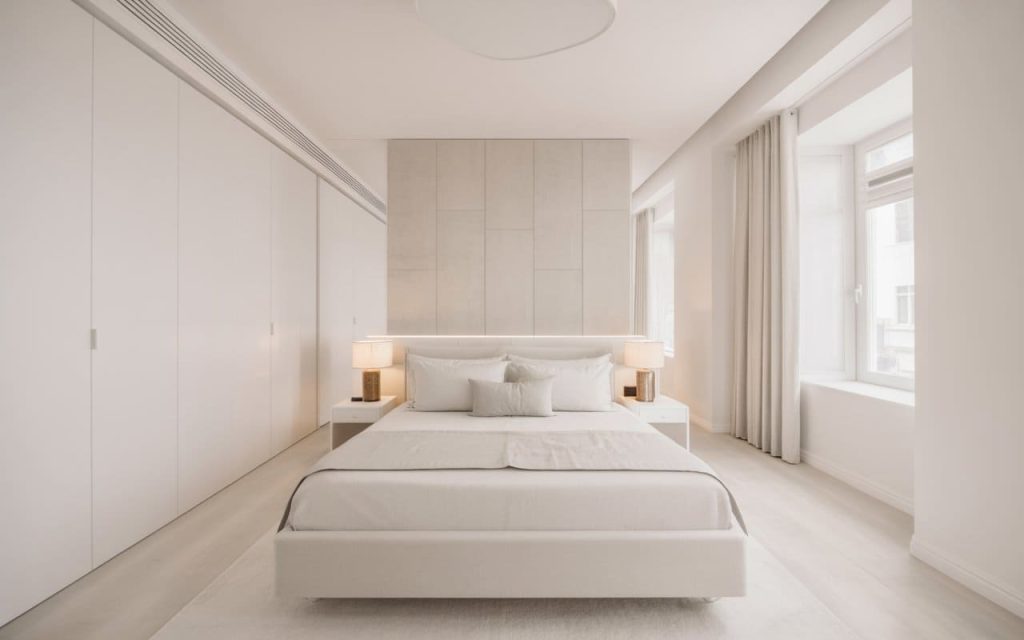 An all-white master bedroom colour combination featuring seamless wardrobes and soft light.