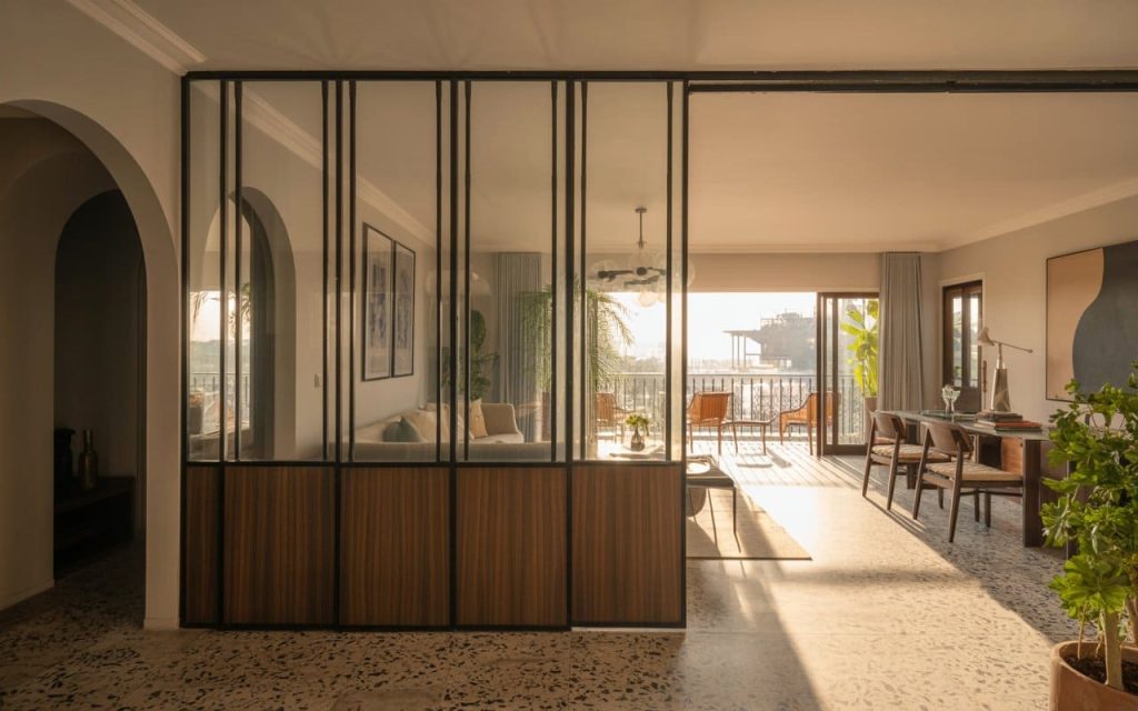 A contemporary wood and glass partition for living room that filters warm evening light.