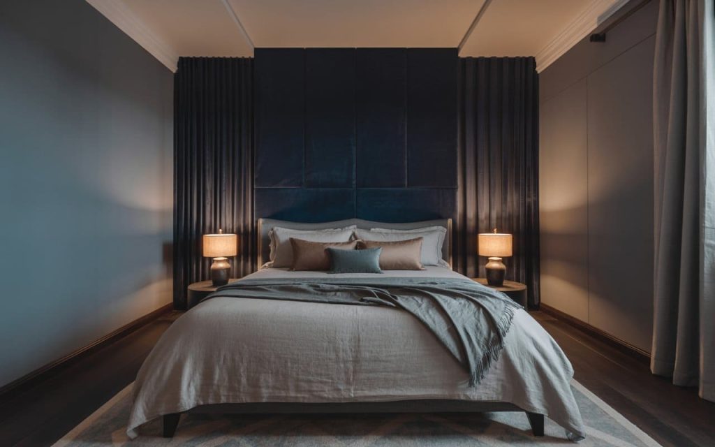 Navy blue and charcoal wall colour combination for master bedroom with warm lighting.