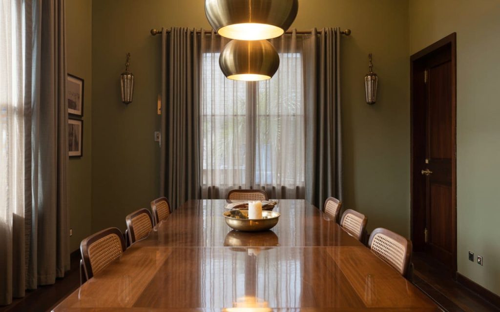 A long wooden dining table reflecting overhead lights after a liquid furniture polish application.