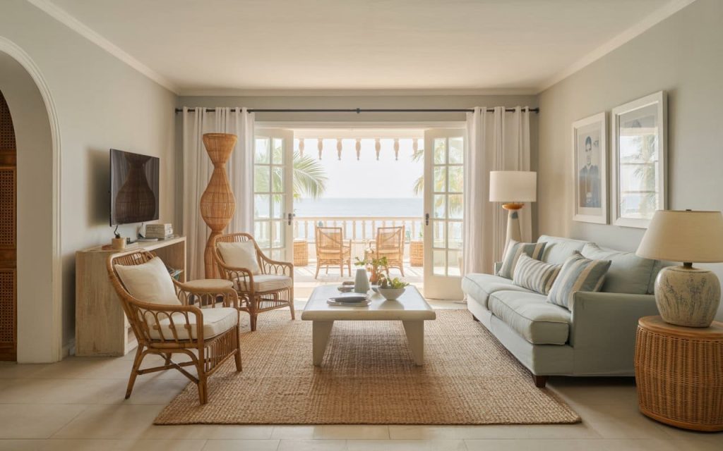Airy grey and blue living room with rattan chairs and a view of the tropical coast.
