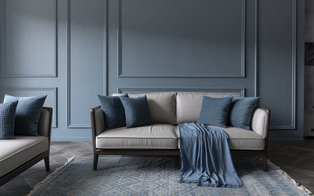 Luxurious dark blue and grey living room featuring ornate wall moulding and a beige sofa.