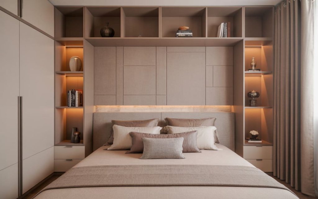 Bedroom wall almirah design integrates beige wardrobe cabinets, lit shelves, headboard, pillows.