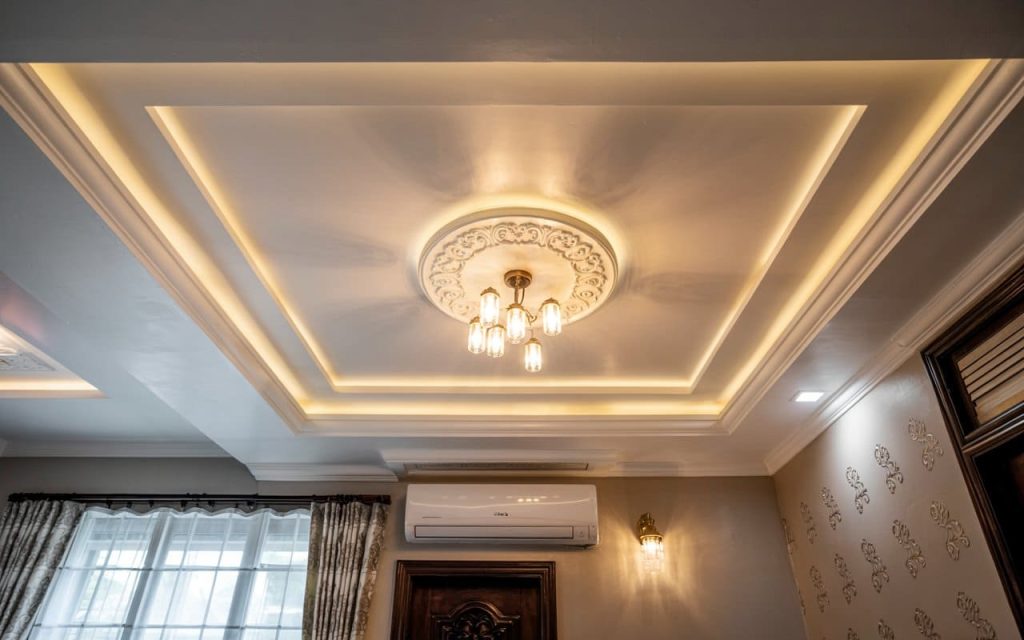 Circular multi-layered pop design for hall featuring a gold chandelier and warm lighting.
